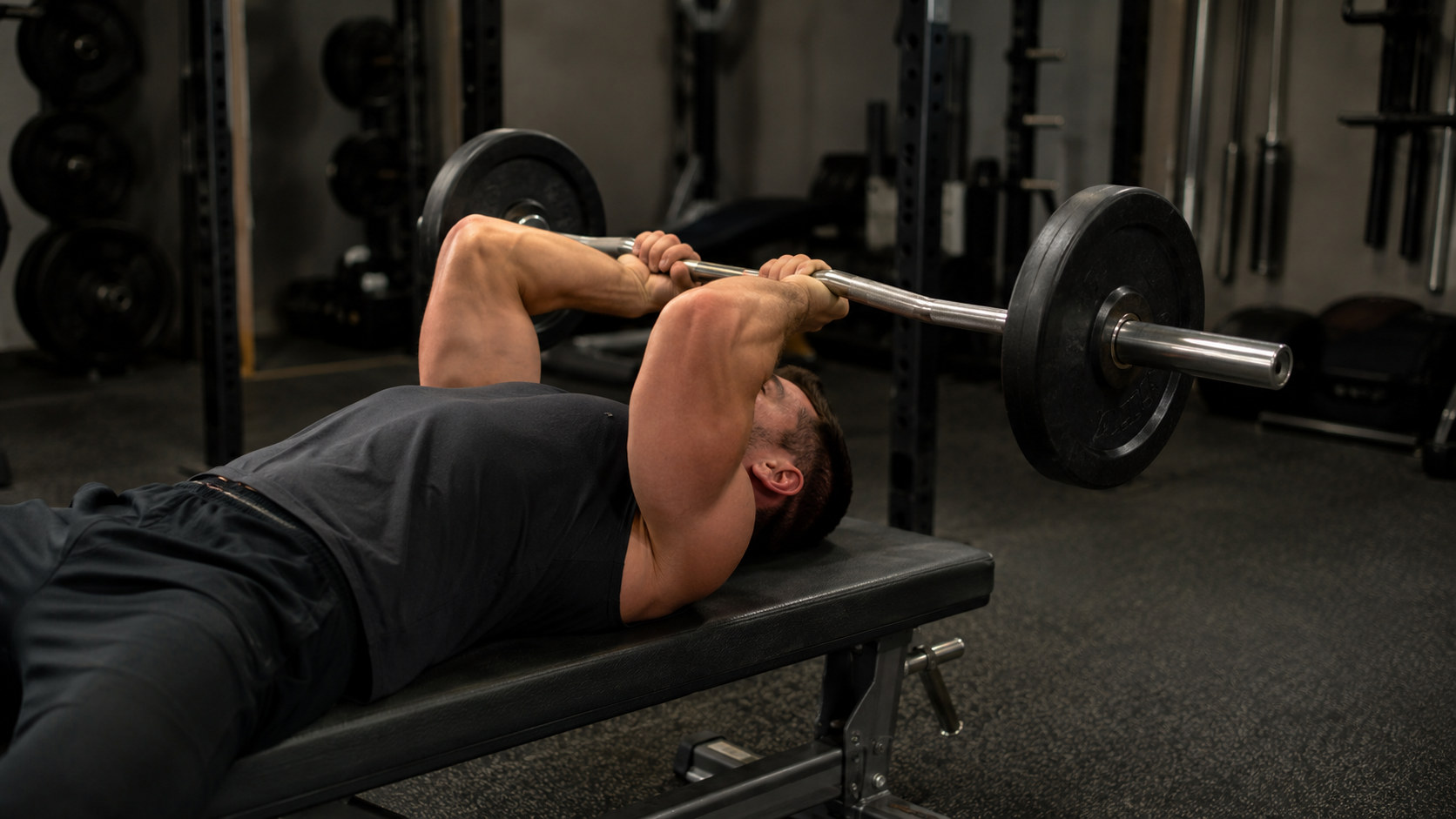 A lifter on a bench lowering a barbell in a lying triceps extension