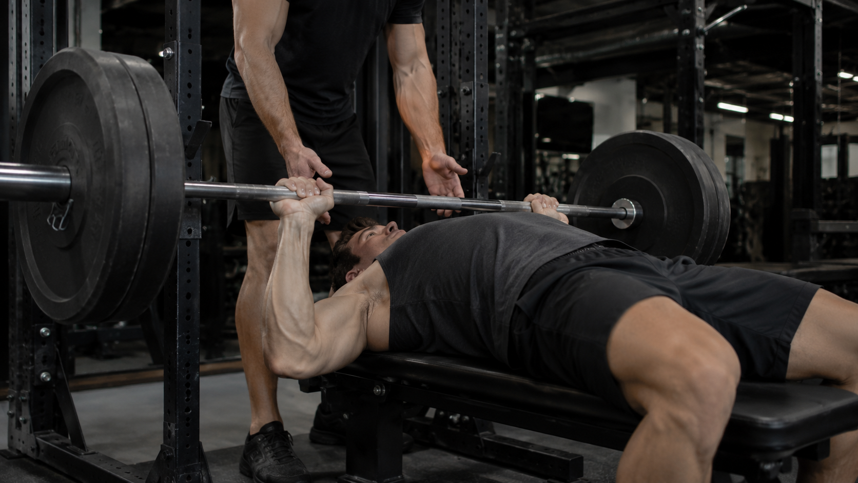 A lifter paused on a flat bench pressing a barbell in a gym
