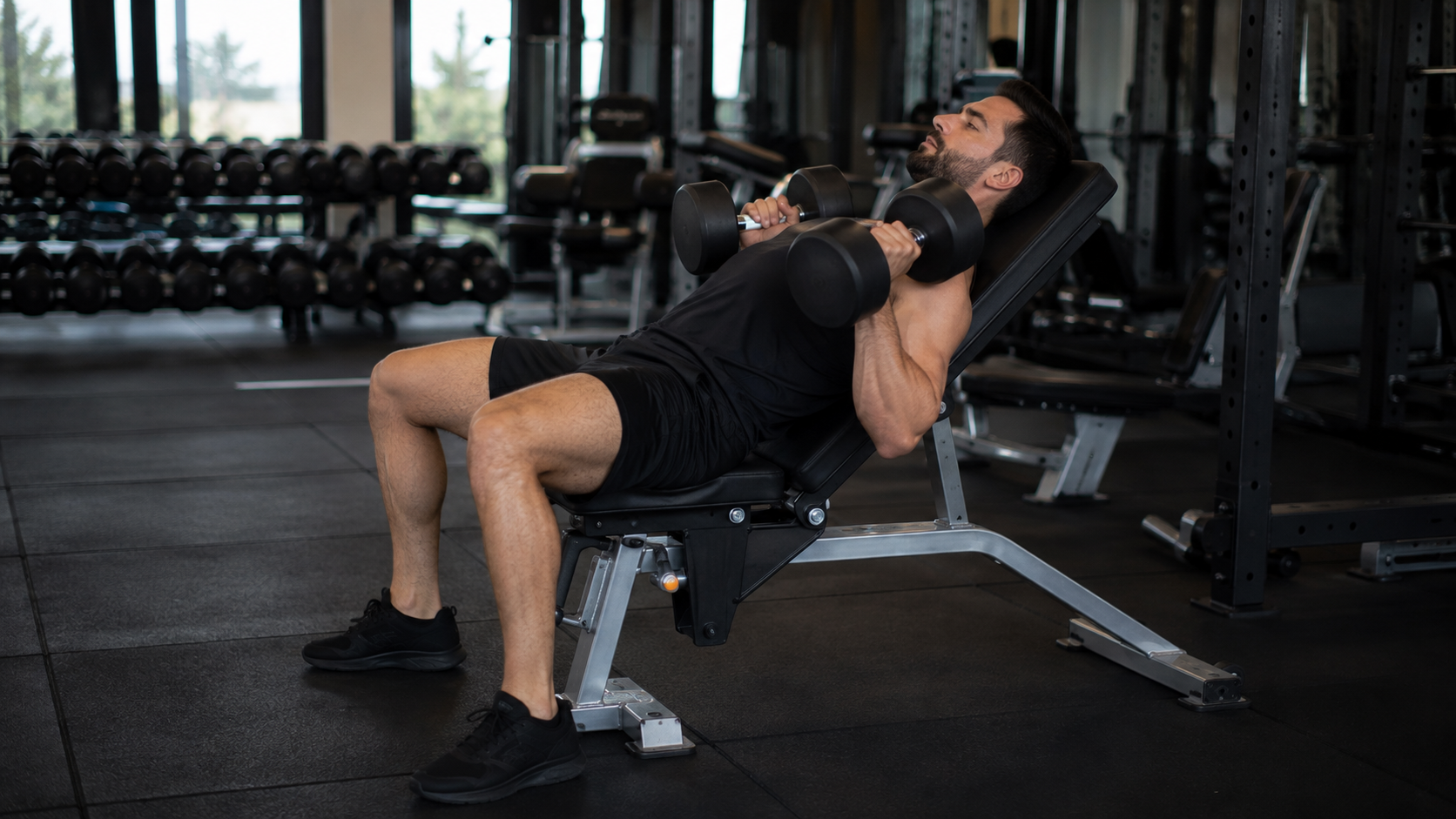 Person pressing dumbbells on a 45-degree incline bench in a gym