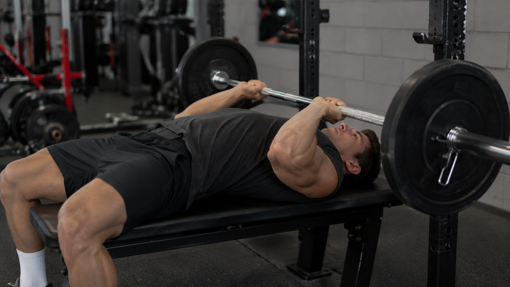 A lifter performing a barbell JM bench press on a flat bench
