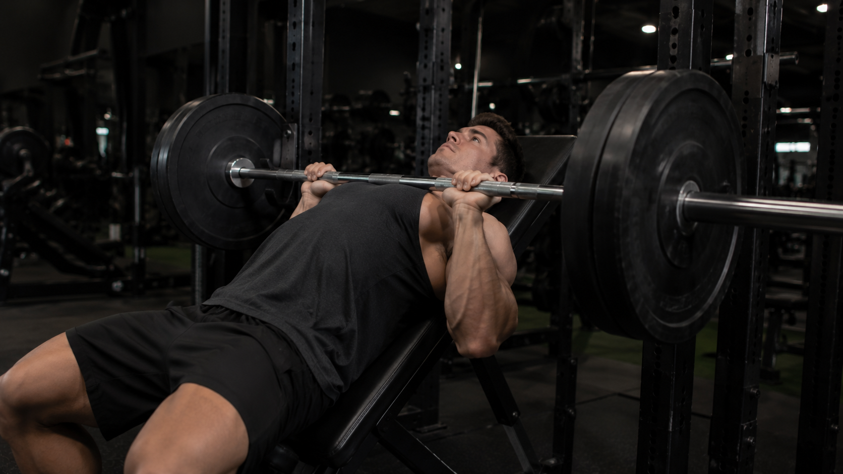 Lifter on an incline bench lowering a barbell toward the upper chest