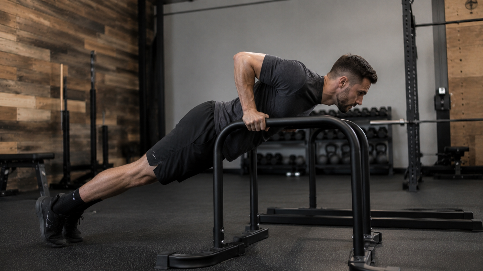 Man pausing at the bottom of a body-up on parallel bars