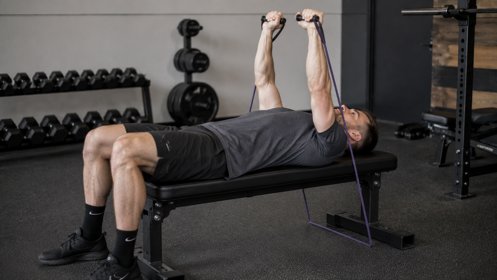 A lifter bench pressing resistance bands with feet planted on a flat bench